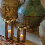 فانوس طرح‌دار کوتاه SA1234 ساختار ترکیبی از چوب و فلز آبکاری شده دارد و در گروه جذاب‌‌ترین مدل‌های فانوس تزئینی قرار می‌گیرد اما نیاز است برای دوام هرچه بیشتر این جذابیت ابتدایی؛ اصول خاص نگهداری از آن را رعایت نمایید. استفاده از آب یا هر محلول شیمیایی دیگر به جهت پاک‌سازی این کالا پروسه‌ای اشتباه و آسیب‌زننده است حتی اگر بهترین متریال ممکن در ساخت آن بکار گرفته شود. می‌توانید در صورت مشاهده کمترین گردوغبار و دوده‌ای با یک دستمال نمدار؛ حالت ابتدایی آن را بازگردانید. این فانوس‌ها با ارتفاع ۴۰ و عرض ۲۰ از پرفروش‌ترین محصولات این مجموعه بشمار می‌رود‌. البته ناگفته نماند که جابه‌جایی این کالا به‌سهولت صورت می‌پذیرد چرا که وزن خالص آن رقم ۱.300 را به خود اختصاص داده است.