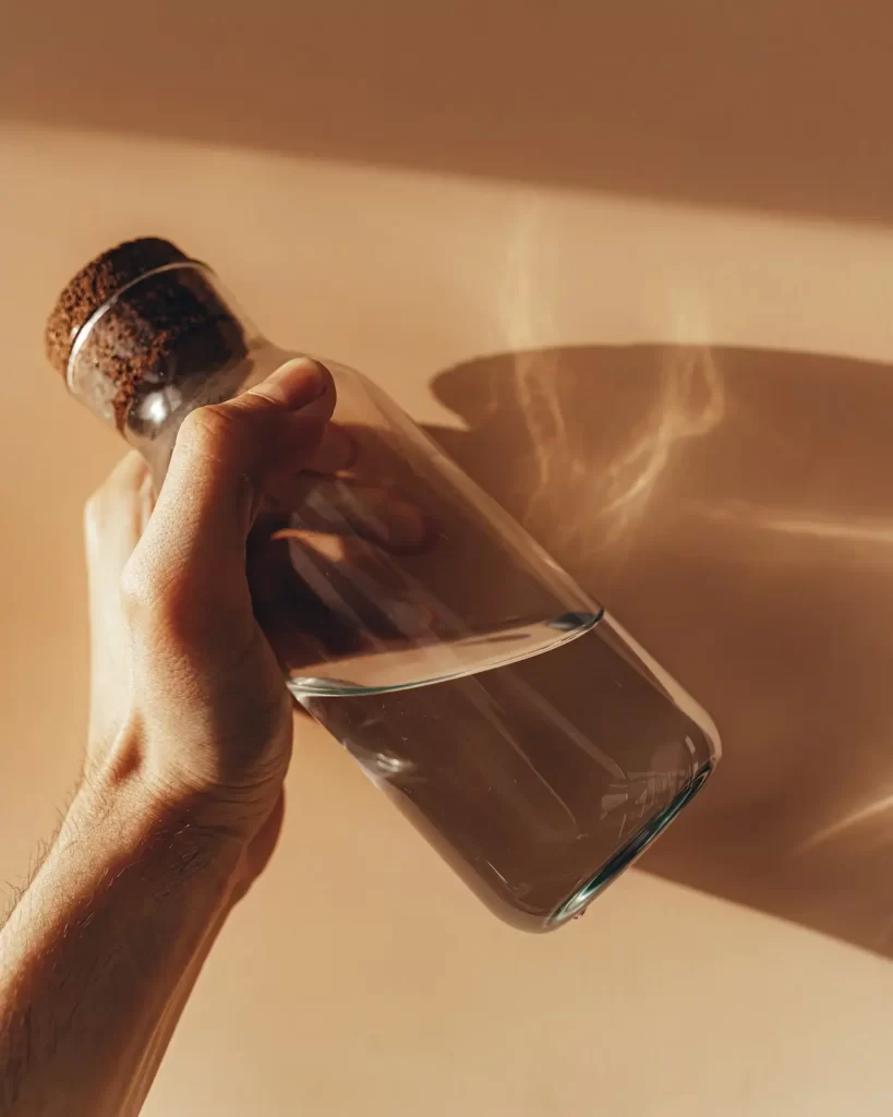 یک بطری شیشه ای آب در دست یک نفر